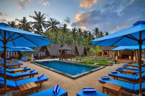 珀尼达岛Mahaloka Valley Nusa Penida的一个带蓝色椅子和遮阳伞的游泳池的度假酒店