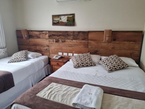洛斯安赫莱斯Hotel Plaza Pinto的客房设有两张床和木墙