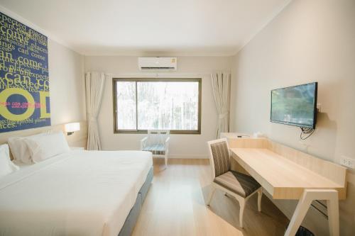 彭世洛帕克酒店的一间卧室配有一张床、一张书桌和一个窗户。