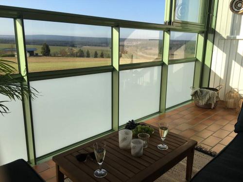 勒芬根Gemütliches Apartment mit wundervollem Weitblick的门廊上设有屏风,配有桌子和酒杯