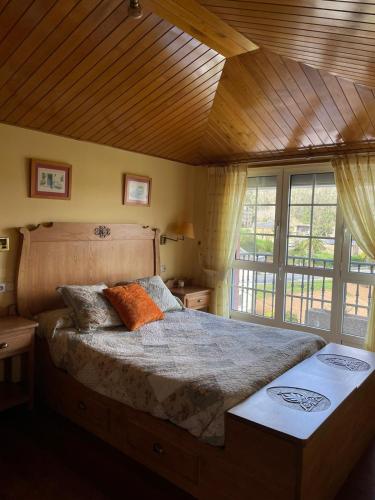 TrabadaCabo de Veiga的一间卧室设有一张带木制天花板的大床