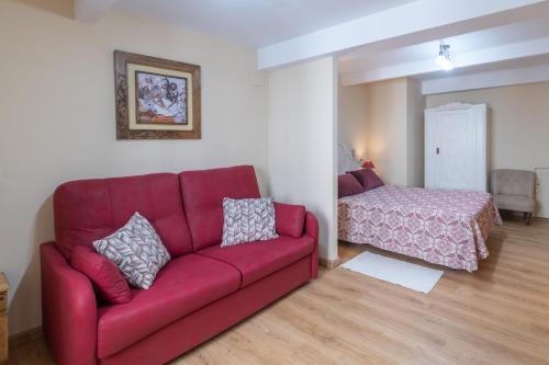 里瓦德塞利亚Belmonte, apartamento en Ribadesella的客厅配有红色的沙发和床。