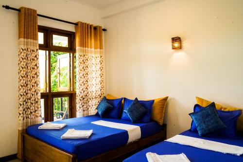 锡吉里亚Sigiri Sierra View Resort的一间卧室设有两张带蓝色床单的床和窗户。
