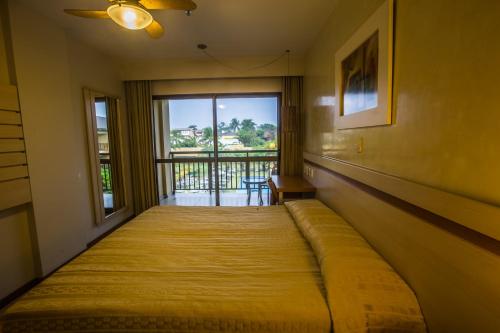 萨尔瓦多卡图萨巴商务酒店的一张大床,位于带大窗户的房间里