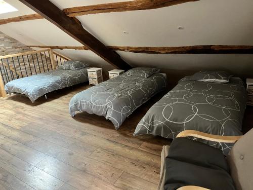 Moulin-MageMaison de campagne的阁楼间设有两张床,铺有木地板