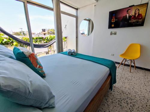 里奥阿查Bona Vida Hotel的一间卧室配有一张大床和一张黄色椅子