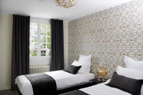沙特尔Les Toits de Chartres - 2 appt - Parking gratuit的一间卧室设有两张床,墙上挂着壁纸。