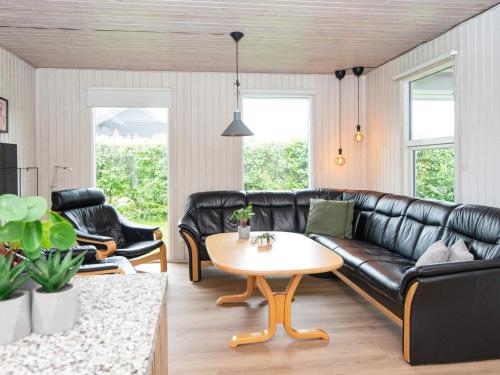 森讷比9 person holiday home in Juelsminde的客厅配有黑色真皮沙发和桌子