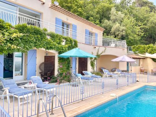 SpéracèdesLes Volets Bleus的房屋旁的游泳池配有椅子和遮阳伞