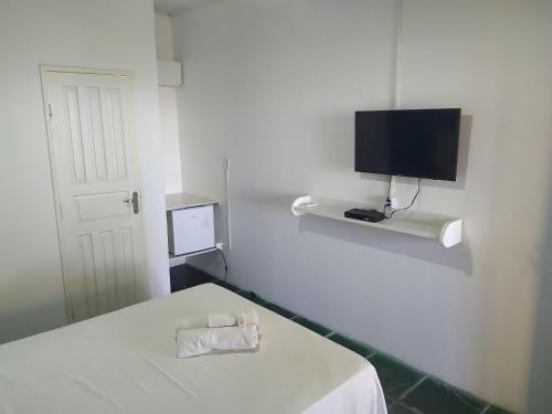 普拉杜Quintal da Praia的白色的客房设有一张床和墙上的电视