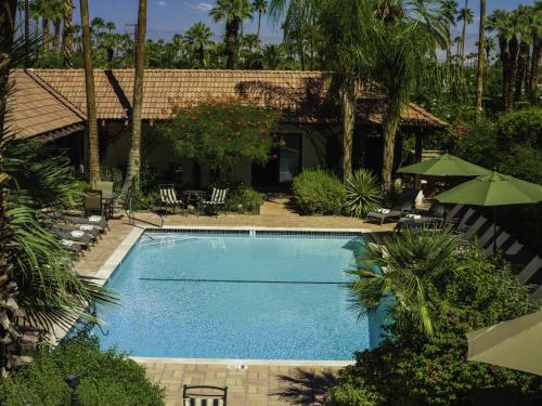 棕榈泉La Maison Hotel - Adults Only的房屋旁的游泳池配有椅子和遮阳伞