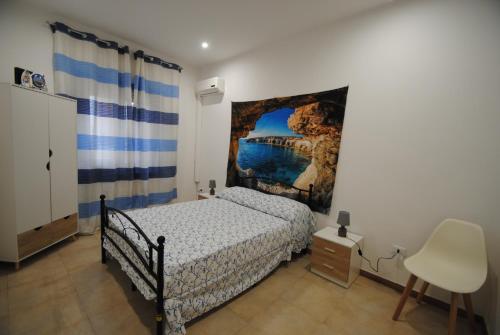 奇尼斯Casa Cinisi - Casa Vacanze的卧室配有一张床,墙上挂有绘画作品
