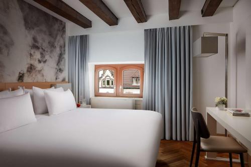 海德堡NH Collection Heidelberg的卧室配有白色的床、书桌和窗户。