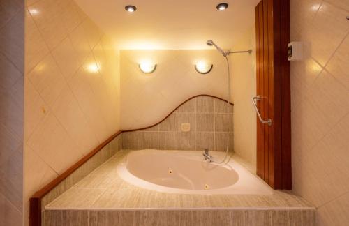 特鲁希略Hotel Country Trujillo的带浴缸的浴室,墙上设有灯