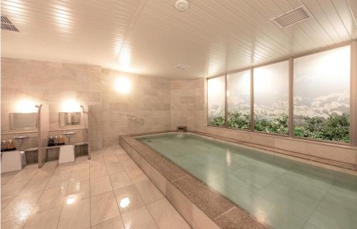 仙台Hotel GrandBach Sendai的大型浴室设有大型窗户和游泳池