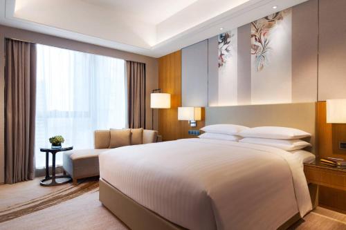 郑州郑州汇艺万怡酒店的卧室配有一张白色的大床和一张沙发。