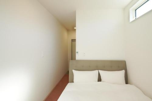 立山町Hotel Cradle Cabin Tateyama的一间卧室配有一张带白色床单的床和一扇窗户。