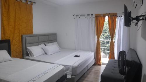 阿瓜奇卡Casa Hospedaje Sandra的一间卧室设有两张床、一台电视和一扇窗户。