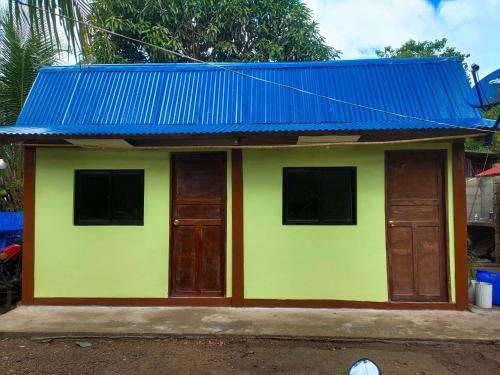布桑加Hondelz Budget Homestay的蓝色屋顶的黄色和绿色小房子