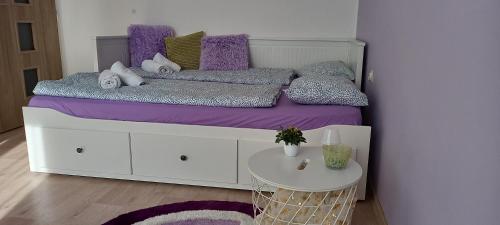 拉贝河畔皇宫镇Garsonka ve Dvoře的一间卧室配有一张带紫色床单的床和一张桌子