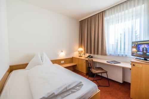 格拉茨克恩布阿姆酒店的酒店客房配有一张床、一张书桌和一台电视。