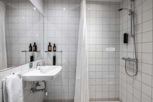 比伦德Airport Hotel, Billund的白色瓷砖浴室设有水槽和淋浴