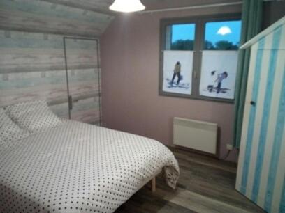 索姆河畔的圣瓦列里Chambre d’hôte的一间卧室配有一张床,还有两张滑雪照片
