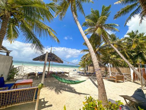 布韦朱The African Paradise Beach Hotel的棕榈树和海洋海滩上的吊床
