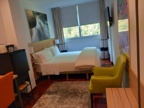 毕尔巴鄂Suite Bilbao Arena con plaza de garaje的卧室配有床、椅子和窗户。