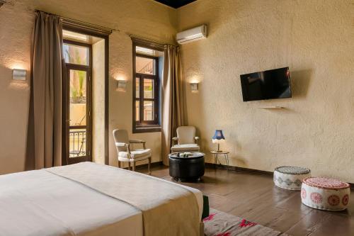 干尼亚阿卡内尔精品酒店的卧室配有一张床,墙上配有电视。