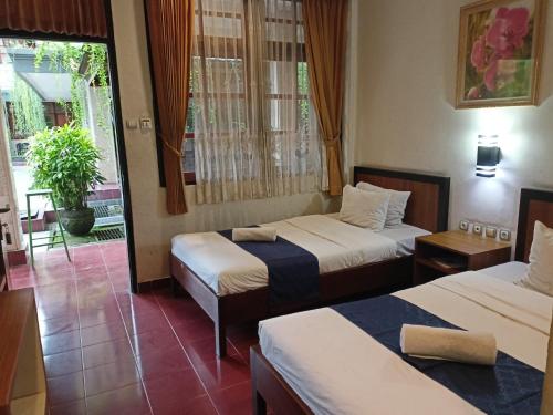 登巴萨Catur Adi Putra的酒店客房设有两张床和窗户。
