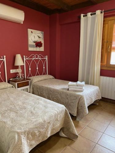 Arens de LledóLA SOCIEDAD的红色墙壁客房的两张床