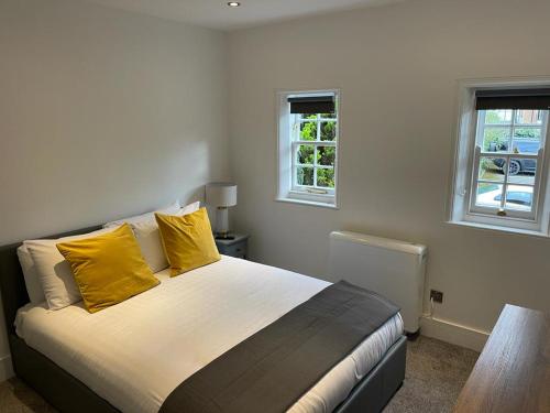 鲍特里Swan House - 5 x Executive Apartments - Central Bawtry的一间卧室配有一张带黄色枕头的床和两个窗户。