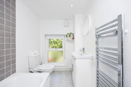 伦敦WelcomeStay Colliers Wood Two Bed Apartment - Home Away from Home的白色的浴室设有卫生间和窗户。