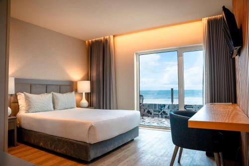 普拉亚达维埃拉Hotel Cristal Vieira Praia & SPA的酒店客房设有一张床,享有海景。
