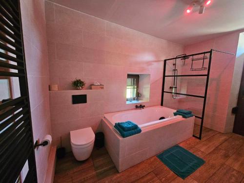 胡法利兹Ferme La Joye的粉红色的浴室设有浴缸和卫生间