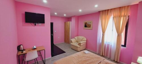 斯库台CityCenterHotel Shkoder的粉红色的房间,配有椅子和墙上的电视