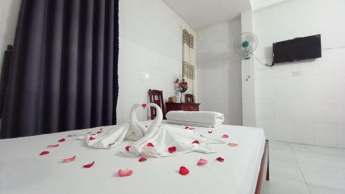 岘港THAI BINH MOTEL的一张白色的床,上面有红色玫瑰花瓣
