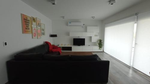 皮拉米德斯港Casa en el mar的客厅配有黑色沙发和电视