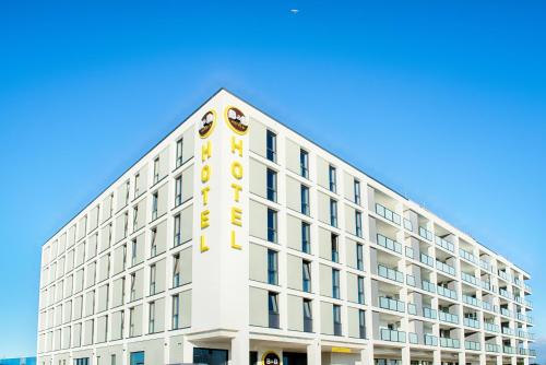 威廉港B&B Hotel Wilhelmshaven的白色的建筑,上面有黄色的标志