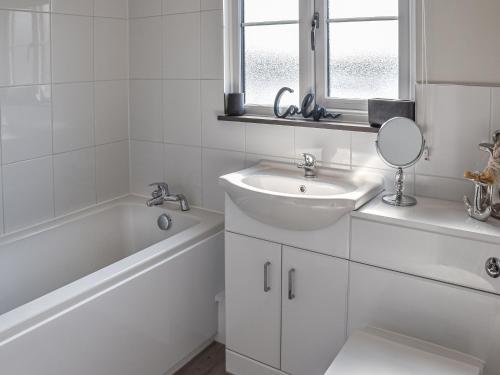 罗克瑟姆Lilys Cottage的白色的浴室设有水槽、浴缸和镜子
