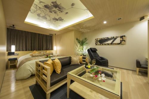 京都绿色情趣酒店（仅限成人）的一间卧室配有一张床、一张沙发和一张桌子