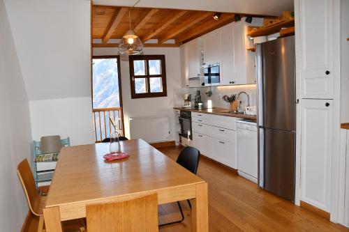 Villard-ReculasAppartement moderne vue imprenable的厨房配有木桌和冰箱。