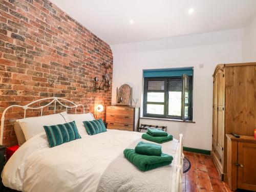 哈斯奥科斯The Masters House的一间卧室设有砖墙和一张带绿色枕头的床