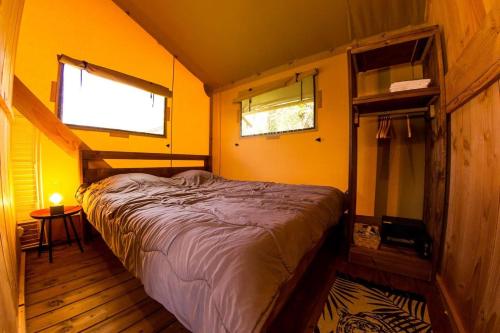 拉戈尔斯Camping et Lodges de Coucouzac的黄色墙壁和2扇窗户的客房内的一张床位