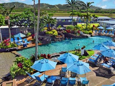 科洛阿Kiahuna Plantation Resort Kauai by OUTRIGGER的度假村内带蓝色椅子和遮阳伞的游泳池