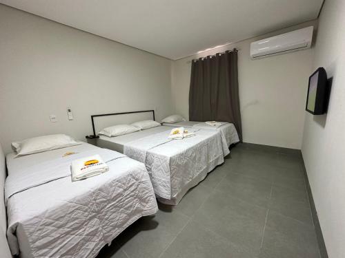 大瓦尔泽亚Hotel Fly - Aeroporto Cuiabá的配有电视的酒店客房内的两张床