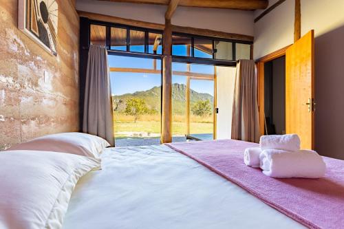 卡瓦坎特Villa Taipas - Chalé Ariê的一间卧室设有一张大床和大窗户