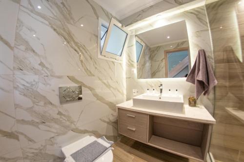 圣斯特凡诺斯Jasmine Hotel & Apartments的一间带水槽和镜子的浴室
