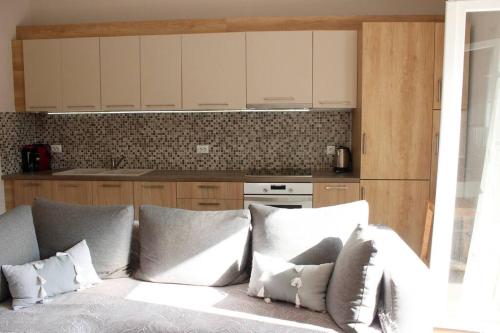希俄斯inHeart Apartment Chios的厨房配有白色橱柜和带枕头的沙发。